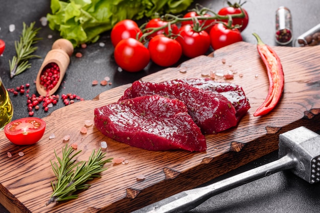 Fresh Raw Beef steak Mignon, with salt, peppercorns, thyme, tomatoes. Raw fresh marbled meat Steak and seasonings