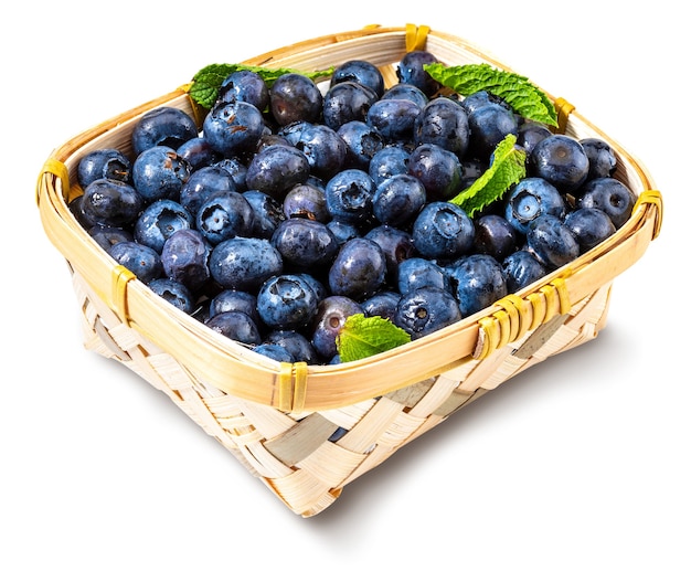 fresh and raw blueberries with drops of water in a small wicker basket isolated on white background