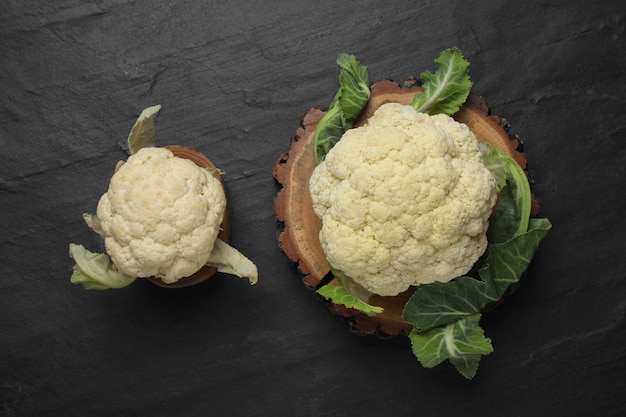 Fresh raw cauliflower cabbages on black table flat lay