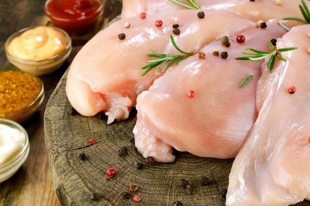 Fresh raw chicken breast fillets sprinkled with peppercorns rosemary and sauces