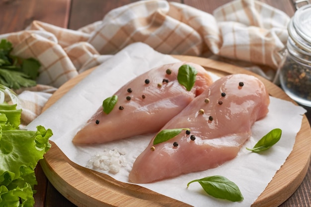 Fresh raw chicken breast mix of pepper lettuce basil rock sea salt brown wooden background