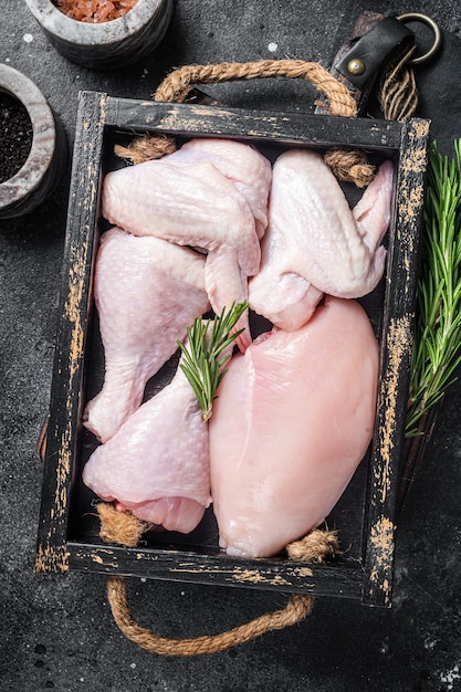 Fresh raw chicken meat and chicken parts drumstick breast fillet wing thigh Black background Top view