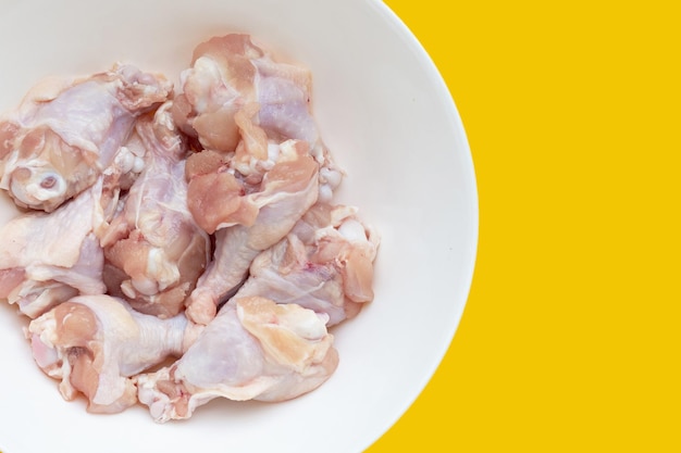 Fresh raw chicken wings wingstick in white plate on yellow background