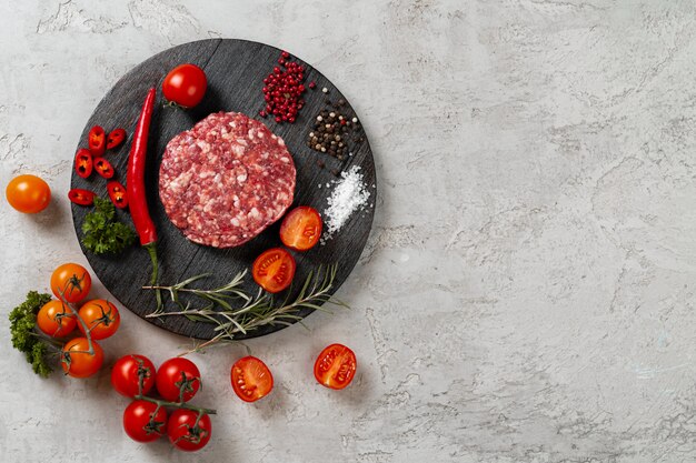 Fresh raw home-made cutlet with spices and tomatoes on the table