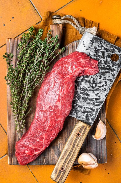 Photo fresh raw machete beef meat steak or hanging tender cut on butcher cutting board orange background top view