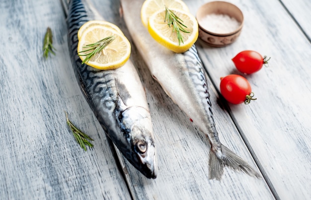 Fresh, raw mackerel with spices, tomatoes, rosemary on a wood background