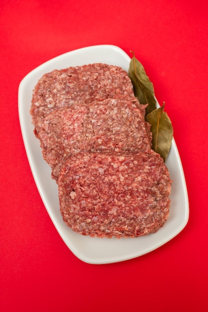 Fresh raw minced meat on white dish with bay leaf