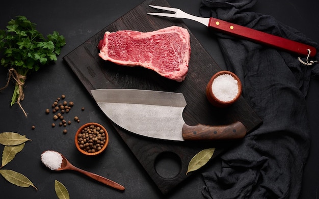 Fresh raw piece of beef meat striploin steak on a black background top view Marbled piece of meat New York