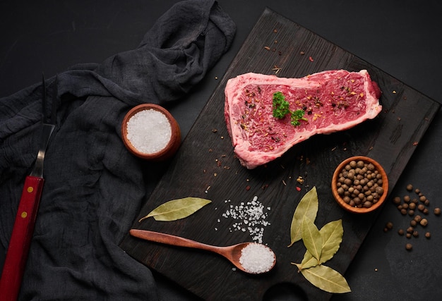 Fresh raw piece of beef meat striploin steak on a black background top view Marbled piece of meat