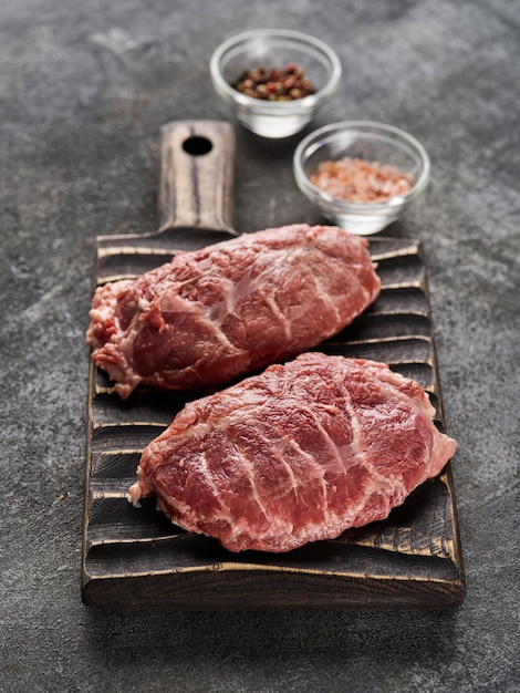 Fresh raw pork cheeks with salt and pepper Grey background