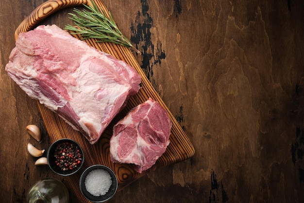 Fresh raw pork neck with salt and pepper overhead shot Pork neck meat on a wooden board top view