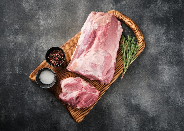 Fresh raw pork neck with salt and pepper overhead shot Pork neck meat on a wooden board top view