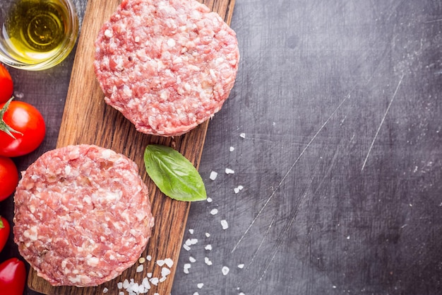 Fresh raw Prime Black Angus beef burger patties on black background. Top view.