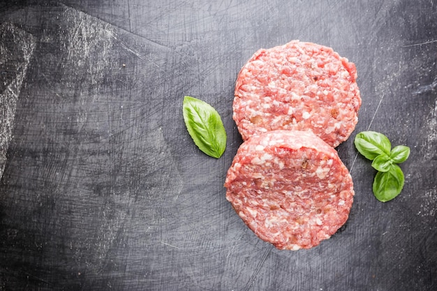 Fresh raw Prime Black Angus beef burger patties on black background. Top view.