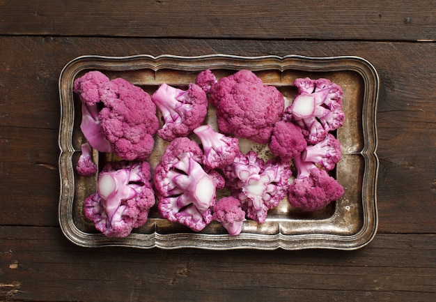 Fresh raw purple cauliflower on a wooden table top view