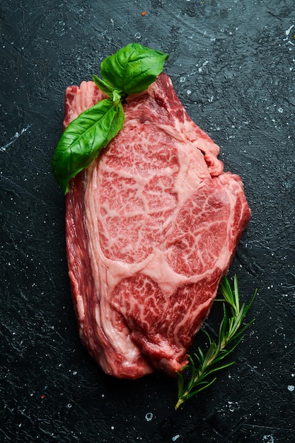 fresh raw rib eye steak Top view On a stone dark background