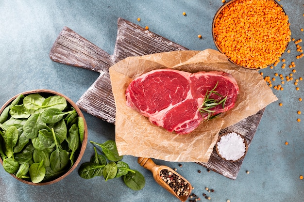 Fresh raw rib-eye steak on wooden cutting board