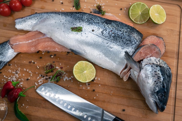 Fresh raw salmon fish on the kitchen wooden board with spices and lime