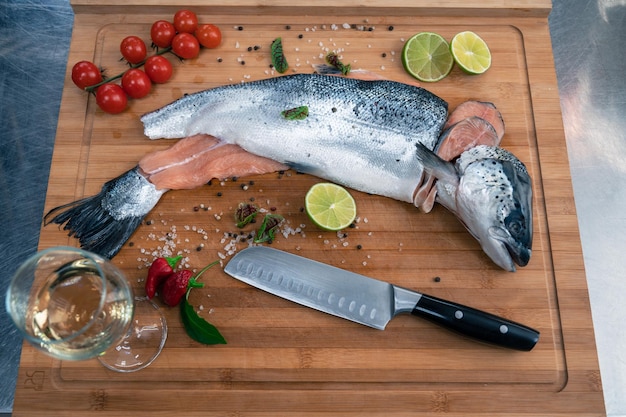 Fresh raw salmon fish on the kitchen wooden board with spices and lime