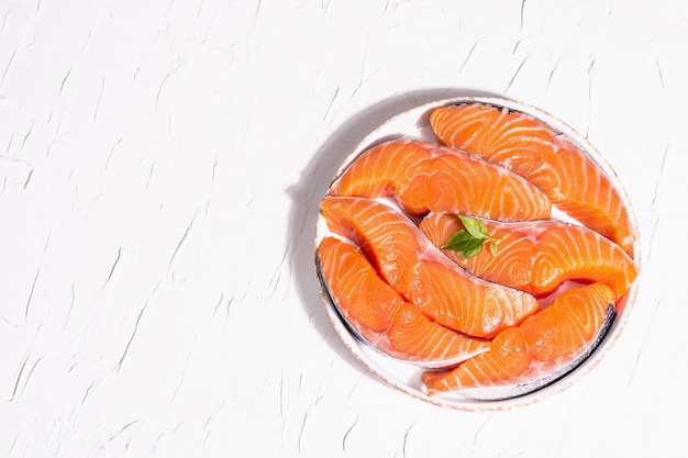 Fresh raw salmon or trout fish fillet steaks. Minimalistic design, modern hard light, dark shadow. Chilled ingredients for cooking healthy seafood. White putty culinary background, top view