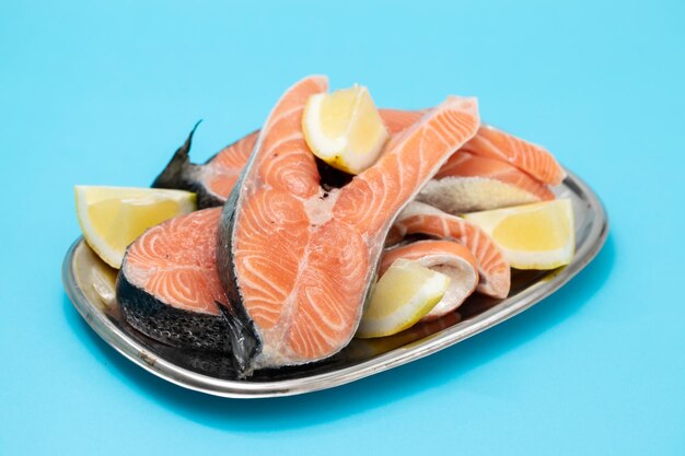 Fresh raw salmon with lemon on the dish on blue