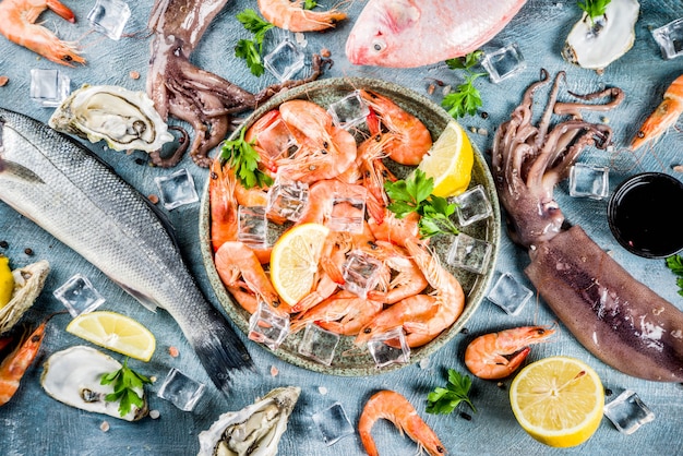 Fresh raw seafood squid shrimp oyster mussels fish with spices of herbs lemon on a light blue background