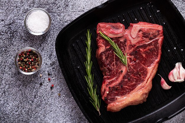 Fresh raw t-bone steak on frying grill pan, top view.