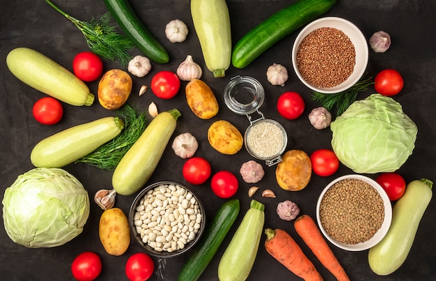 Fresh raw vegetables in assortment on black background in flat lay. Vegetarian concept