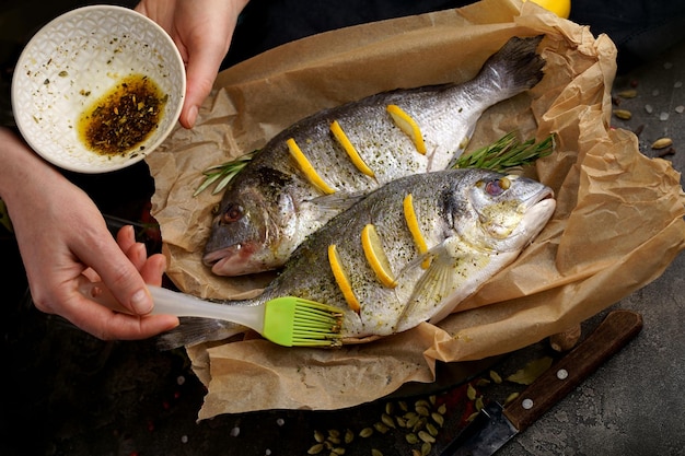 Fresh ready to cook raw bream fish dorado with ingredients and seasonings like rosemary salt pepper lime and olive oil top view