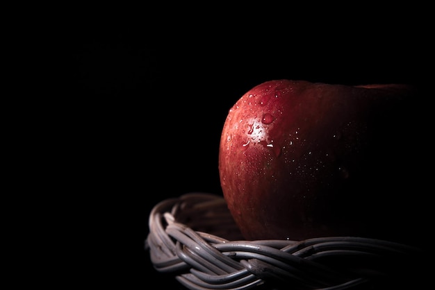 fresh red apples in basket with water droplets on black background There is space for text.