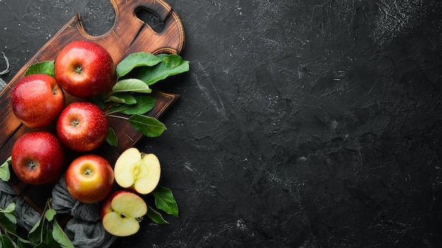 Fresh red apples with green leaves on a black background Fruits Top view Free space for text