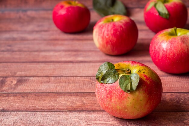 Fresh red apples with green leaves on a Dark wooden table.