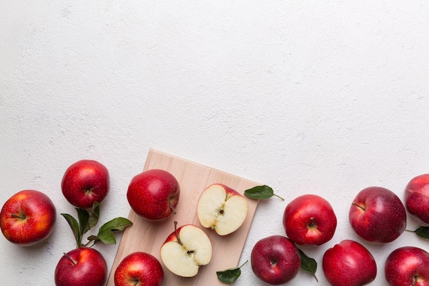 Fresh red apples with green leaves on table cutting board with knife Top view