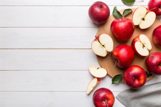 Fresh red apples with green leaves on table cutting board with knife Top view