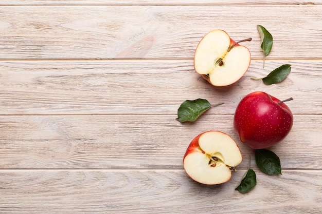 Fresh red apples with green leaves on wooden table. On wooden background. Top view free space for text