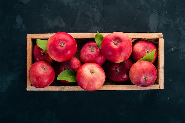 Fresh red apples in a wooden box Organic food On a black background Top view Free space for text