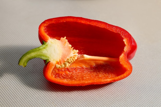 Fresh red bell pepper, cut in half, cavity inside, seeds. Close-up on a gray background.