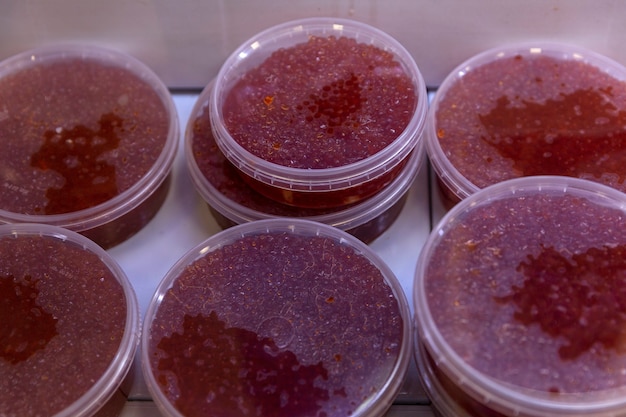 Fresh red caviar in plastic containers on the counter. An expensive delicacy.