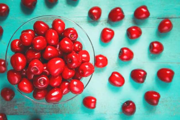 Fresh red cherry in a bowl on an old painted wooden table as a bright colorful summer background