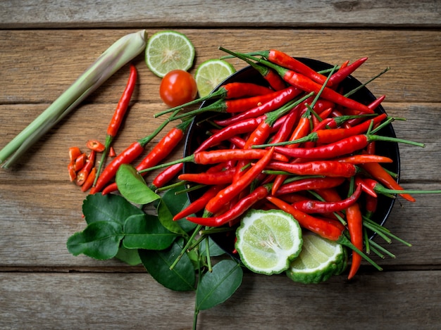 Fresh red chili peppers in a black cup on old wood table background. top view