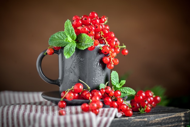 Fresh red currants in a Cup on a dark rustic wooden table. 