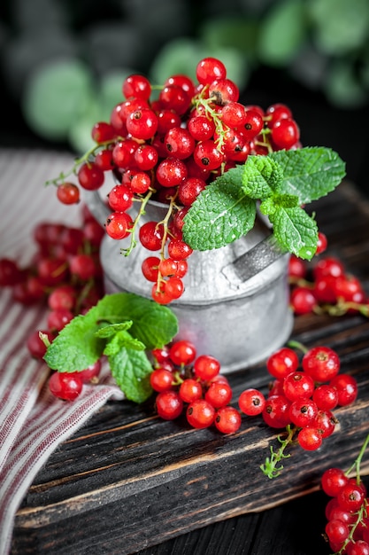 Fresh red currants in a Cup on a dark rustic wooden table. 