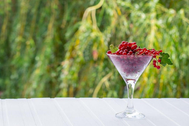 Fresh red currants in a glass beaker on a kitchen wooden table