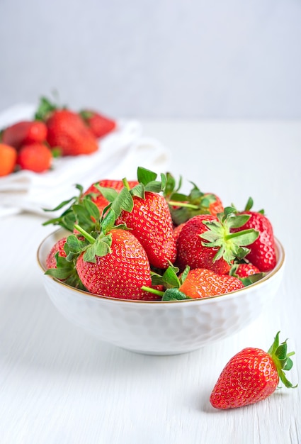 Fresh red garden strawberries with juicy texture and sweetness served in bowl on white wooden table