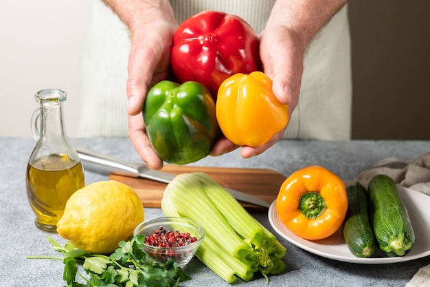 Fresh red green and yellow peppers zucchini and celery in the hands of the chef