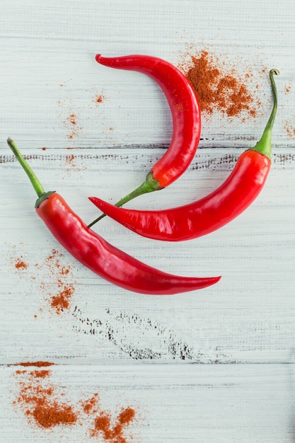 Fresh red hot chili peppers and dried paprika on a white wooden table