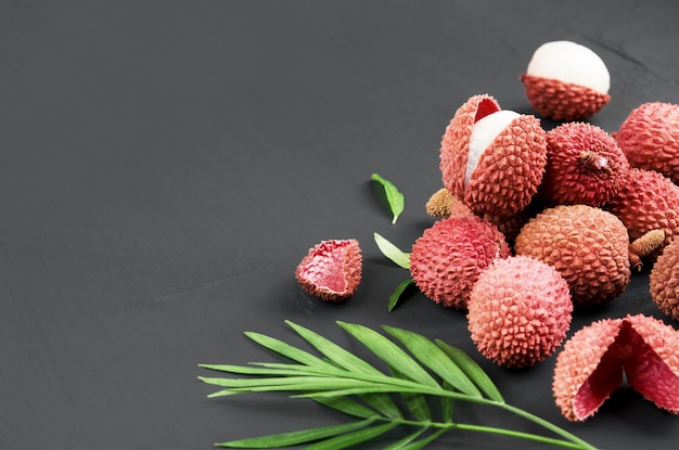 Photo fresh red lychee fruits with leaves on a dark background exotic healthy berry top view copy space