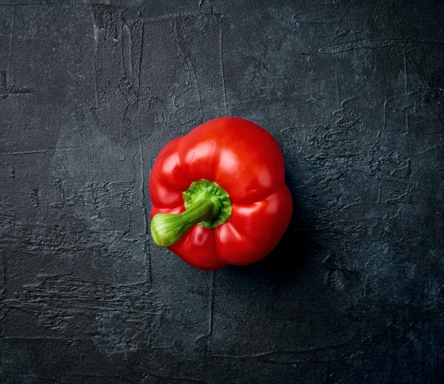 Fresh red paprika on black painted background, top view