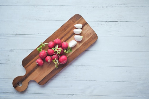 Fresh red radish bundle on chopping board on table