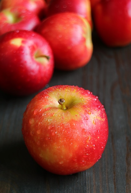 Fresh ripe apples with water droplets isolated on black wooden table